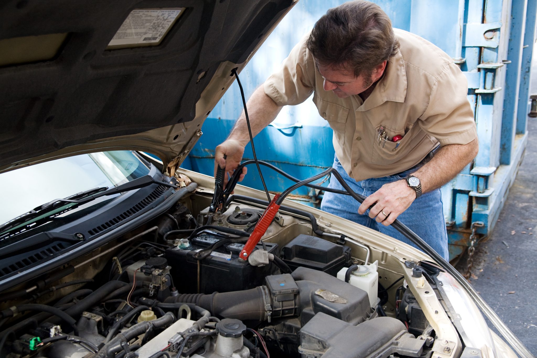 Auto mechanic using jumper cables