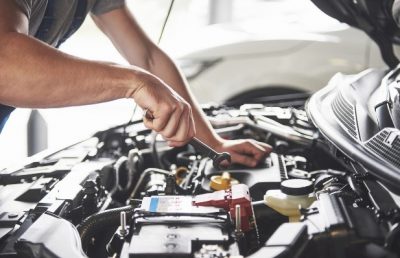 technician working under hood of car